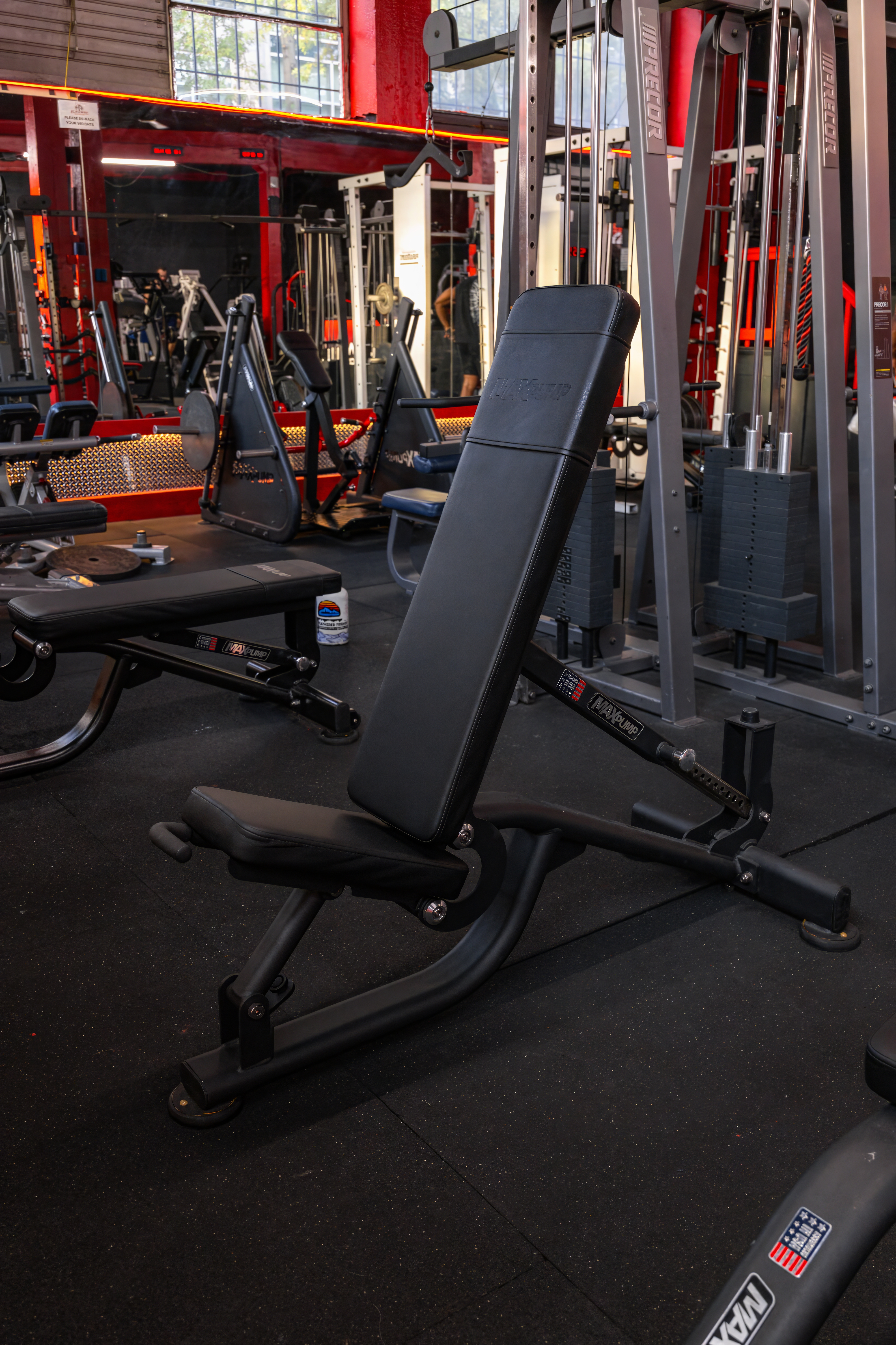 Adjustable commercial-grade utility bench by Maxum on the workout floor, perfect for incline, decline, and flat exercises