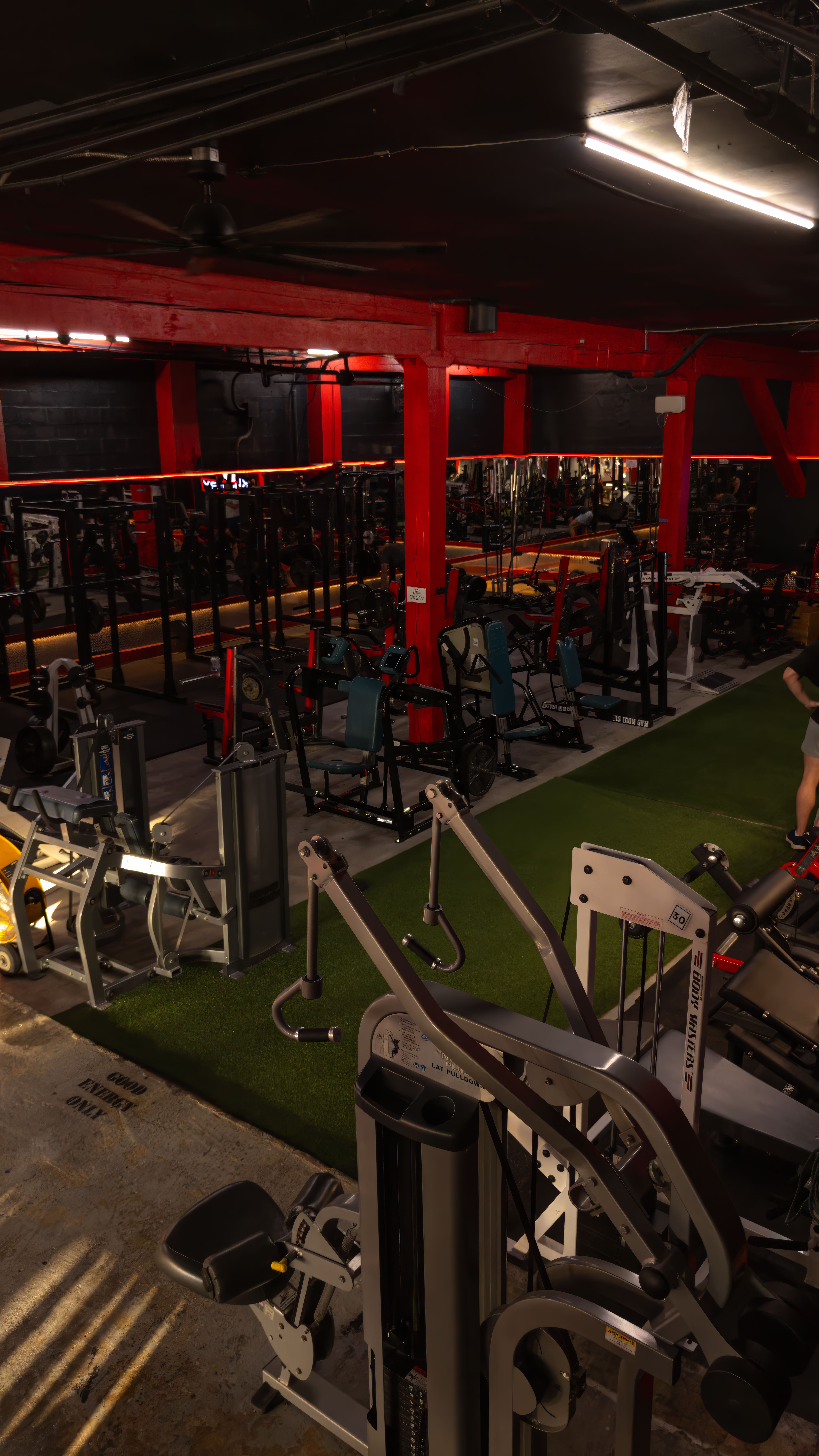 Full overview of the KlickWay Athletics training floor, showing the dedicated indoor turf lane flanked by a wide selection of selectorized and plate-loaded strength machines