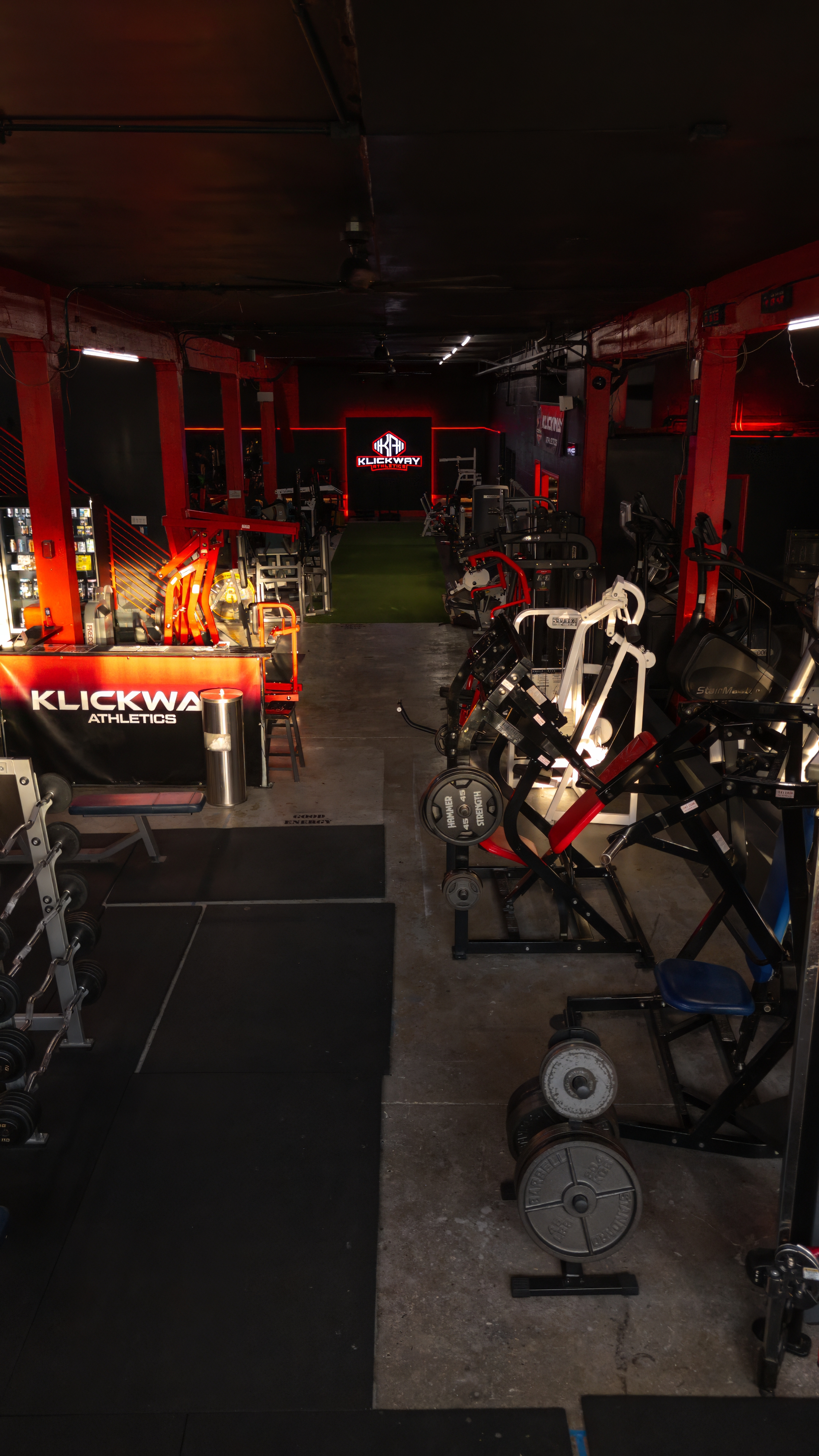 Wide-angle view of the main machine aisle at KlickWay Athletics Seattle, showcasing rows of professional-grade strength training equipment