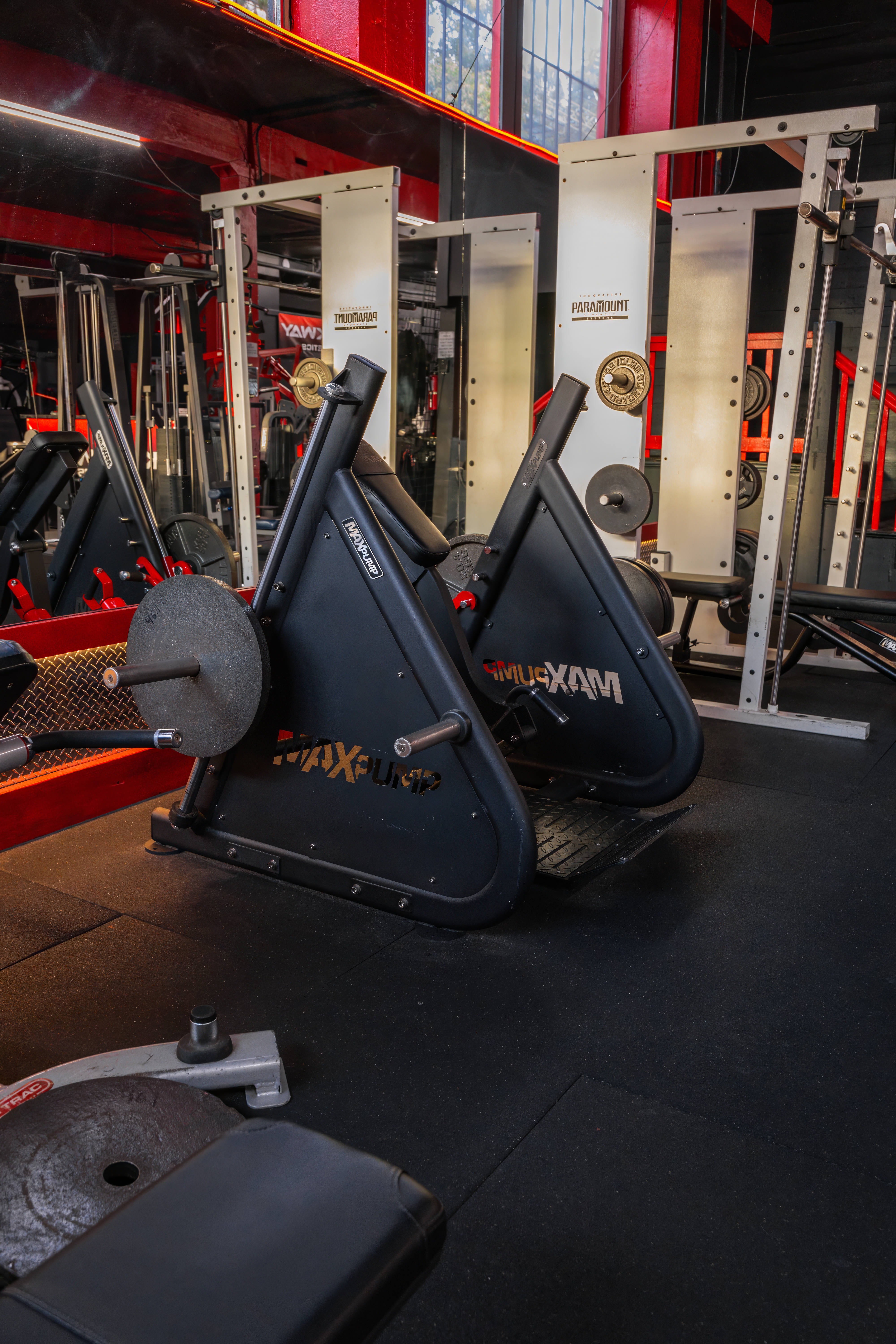 Close-up of specialized lower body machines on the strength floor, featuring two MaxPump leg press machines