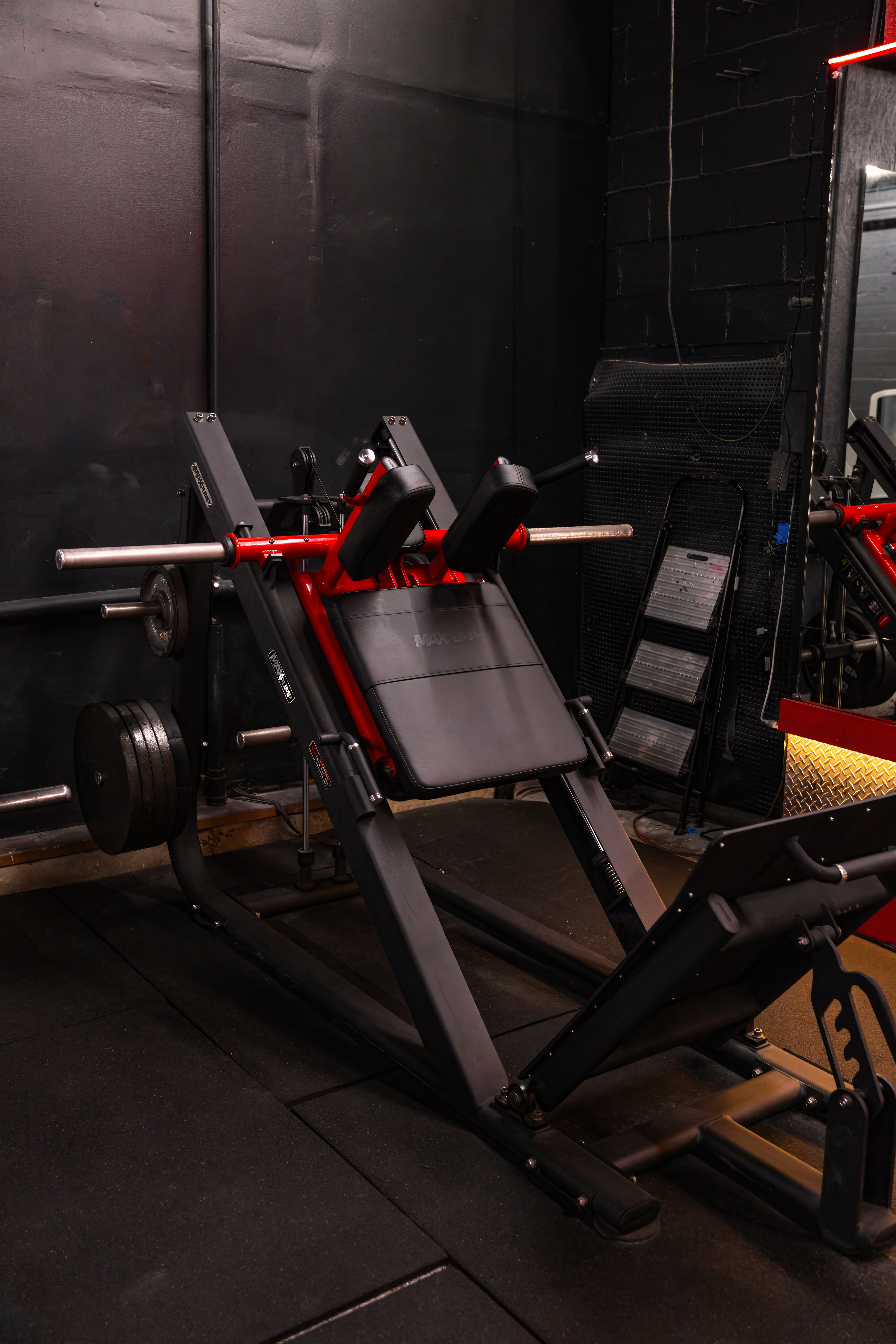 Close-up of the Maxum plate-loaded hack squat machine, featuring a comfortable angled back pad and shoulder pads for focused quad and glute development