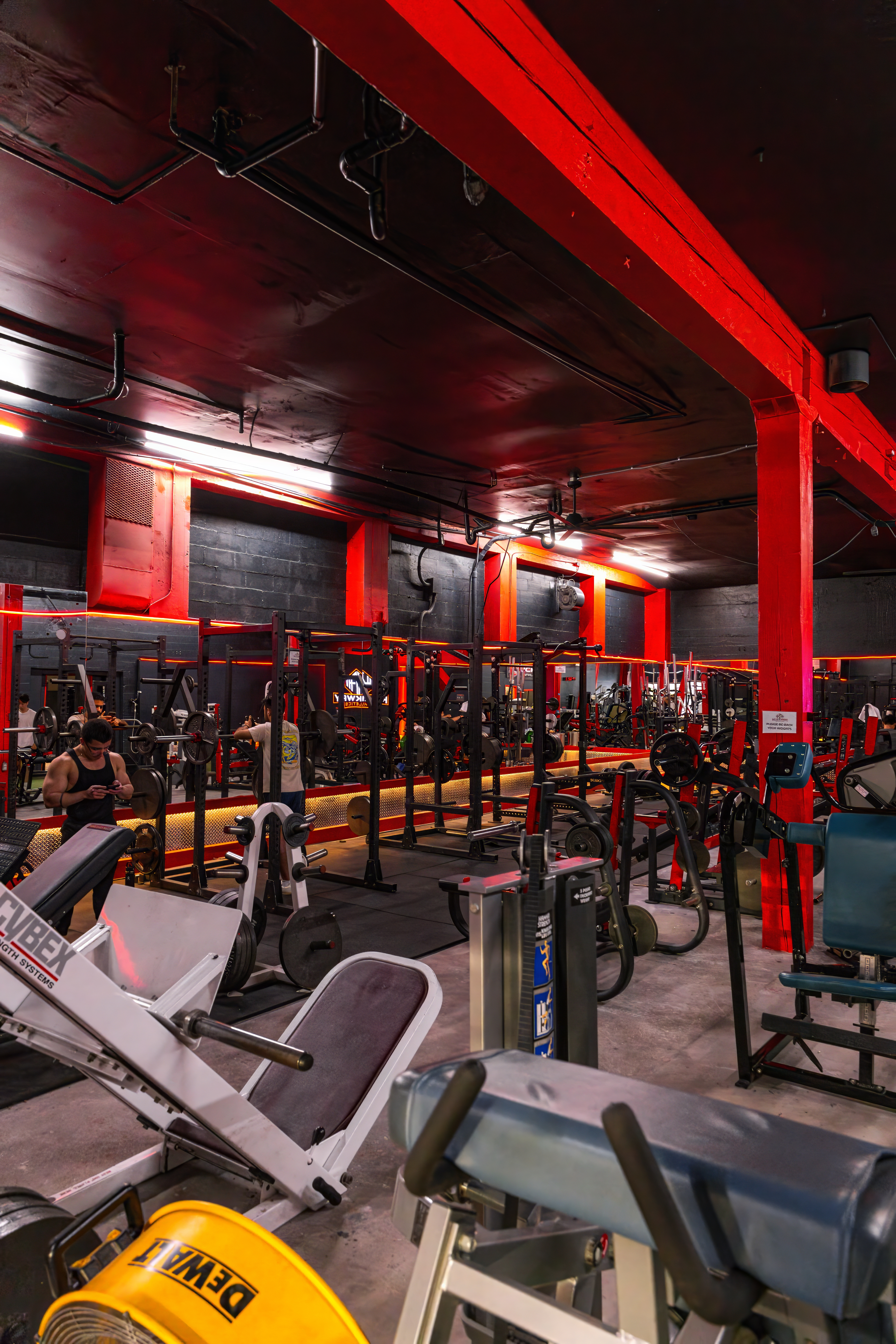 Wide view of the strength training floor at KlickWay Athletics, showcasing a long row of power racks and squat cages for safe, intensive heavy lifting